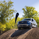 A blue 2023 Kia Telluride SX X-Pro parked at the top of a steeply sloped pile of dirt at an off-road course.